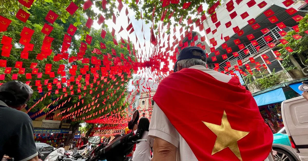 Affichage dynamique de drapeaux vietnamiens lors d'une célébration de rue, symbolisant la fierté nationale.